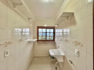Interior de um banheiro com paredes de azulejo branco e janela.