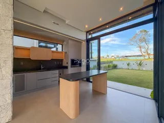 Interior de uma sala de estar com cozinha e vista para o jardim de uma residência em Lajeado.