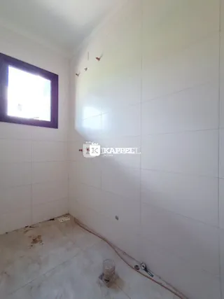 Ambiente interno com paredes brancas e piso claro em uma residência.