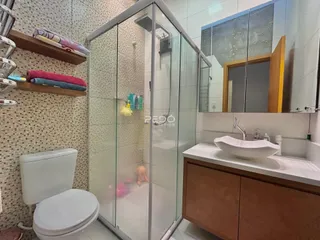 Banheiro com box de vidro e revestimento cerâmico na residência.