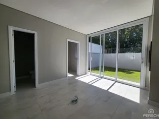 Sala de estar com piso de porcelanato e porta de vidro que dá para o jardim.
