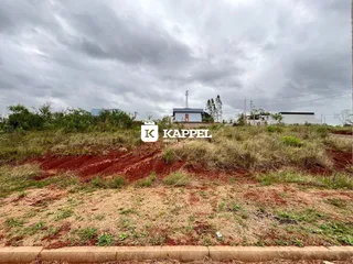 Vista externa de um terreno com vegetação seca sob um céu nublado.