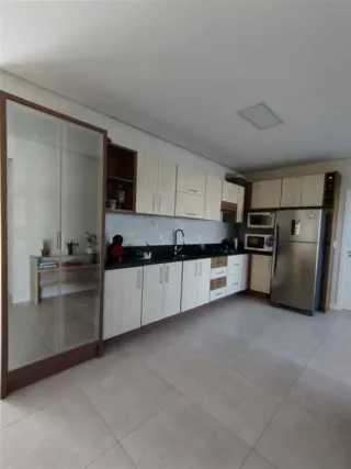 Foto interna de uma cozinha com armários brancos e piso de cerâmica.