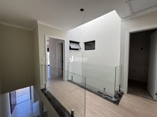 Hall de entrada com piso de madeira e guarda-corpo de vidro.