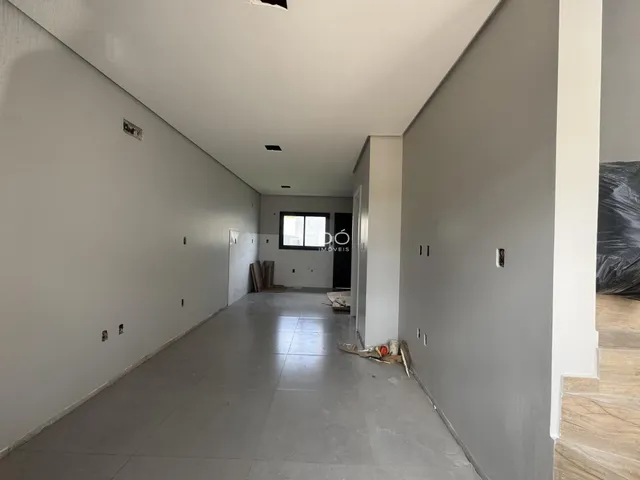 Corredor interno de uma residência com paredes brancas e piso claro.