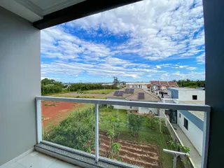 Vista panorâmica de uma área externa com vegetação e edifícios ao fundo.
