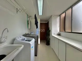 Interior de uma área de serviço com máquina de lavar e pia em um imóvel no Brasil.