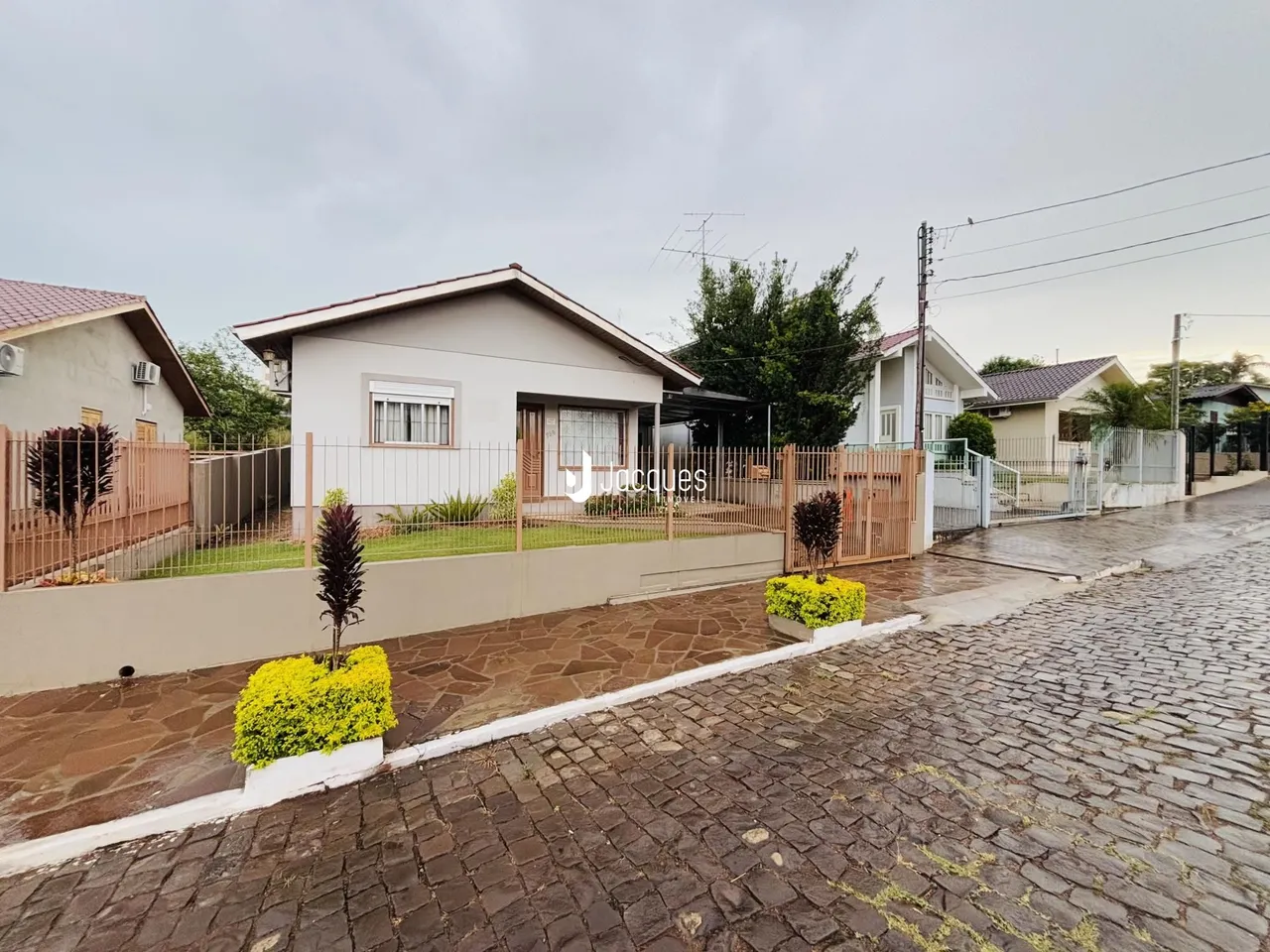 Fachada de uma casa em Lajeado, Brasil, com cerca e jardim na frente.