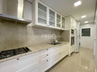 Cozinha moderna com armários brancos e bancadas claras.