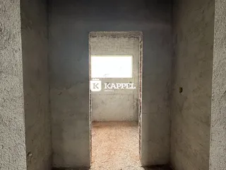 Foto de um corredor com paredes de concreto aparente e uma abertura para outro espaço.