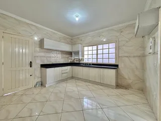 Imagem de uma cozinha com revestimento de cerâmica clara e armários brancos.