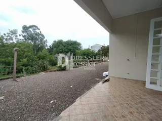 Vista externa do terreno com cascalho e vegetação.