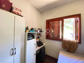 Quarto interno com armário branco e janela de madeira.