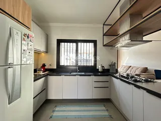 Vista da cozinha moderna com armários brancos e bancadas escuras.