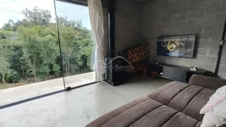 Uma sala de estar com grande porta de vidro oferece uma vista para a vegetação exuberante.