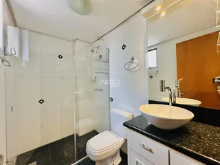 Banheiro moderno com box de vidro e revestimento branco.