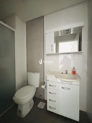 Foto de um banheiro com vaso sanitário e pia de bancada branca.