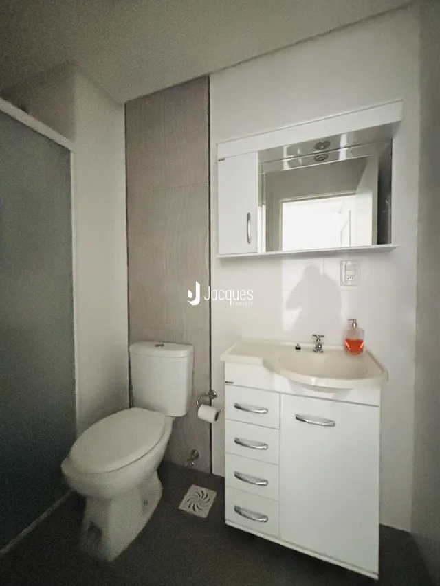 Foto de um banheiro com vaso sanitário e pia de bancada branca.