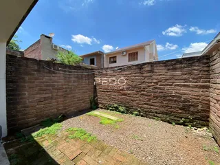 Parede de tijolos de cor avermelhada com jardim e terra no quintal.