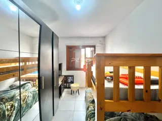 Foto de um quarto com beliches de madeira e paredes brancas.
