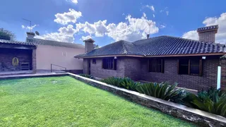 Fachada de uma residência com telhado de telhas escuras e um gramado verde bem cuidado.