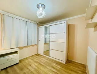 Quarto com piso de madeira e armário branco em um imóvel no Brasil.