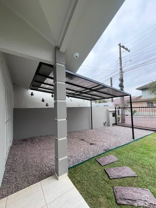 Vista de uma área externa coberta com piso de cimento e gramado em uma propriedade em Lajeado.