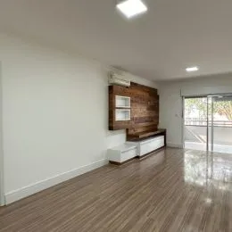 Foto interna de um ambiente com piso de madeira e parede de destaque.