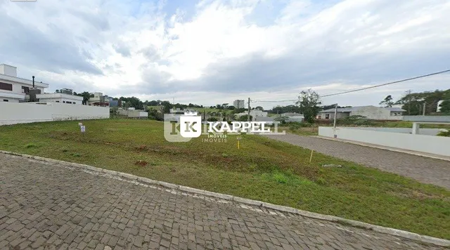 Vista externa de um terreno com grama e área pavimentada.