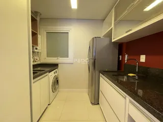 Vista interna de uma cozinha com armários brancos e piso claro.