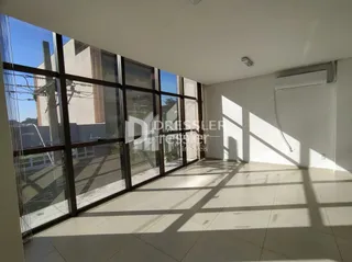 Sala com grandes janelas de vidro iluminada pela luz do sol.