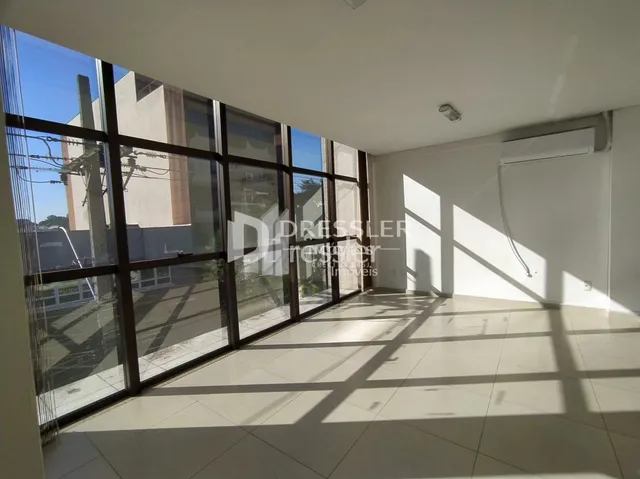 Sala com grandes janelas de vidro iluminada pela luz do sol.