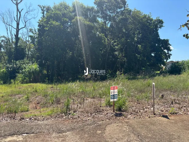 Vista externa de um terreno com vegetação densa e sinalização no meio-campo.