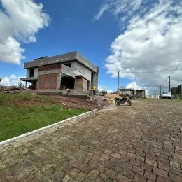 Vista externa de uma propriedade em Lajeado, com terreno inclinado e pavimentação de tijolos.