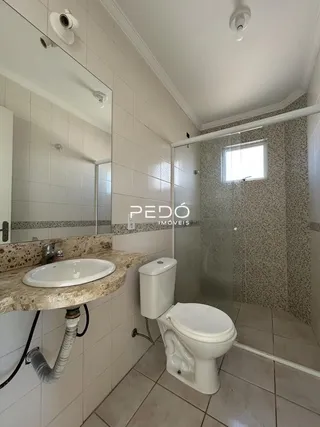 Foto interna de um banheiro com revestimento cerâmico e box de vidro.
