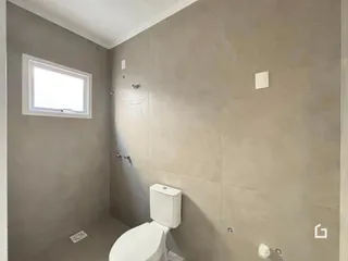 Foto de um banheiro interno com parede cinza e janela.