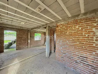 Área interna com paredes de tijolo aparente e estrutura de concreto exposta.