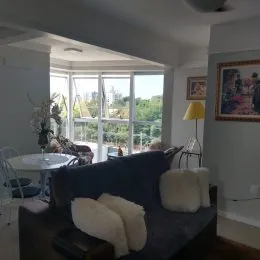 Foto de uma sala de estar com sofá e grandes janelas.