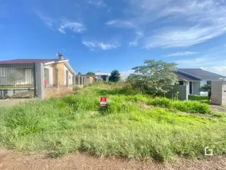 Vista externa de uma propriedade com grama alta em primeiro plano.
