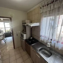 Ambiente interno com piso de cerâmica e cortinas brancas.