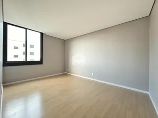 Uma sala de estar ampla com piso de madeira clara e grande janela.