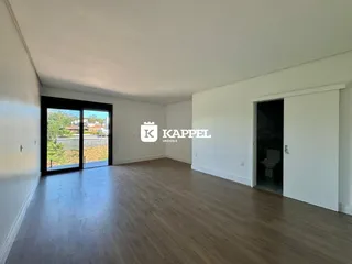Sala ampla com piso de madeira e porta de vidro que dá para a área externa.