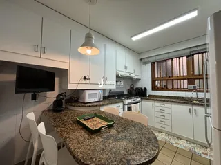 A cozinha apresenta armários brancos e uma ilha de granito com uma mesa de jantar.