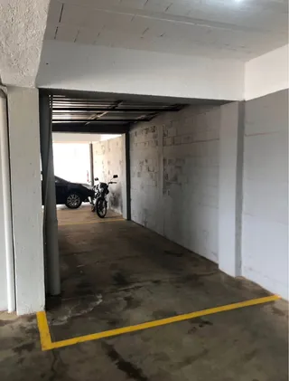 Foto de uma área de garagem com piso de concreto e estrutura branca.