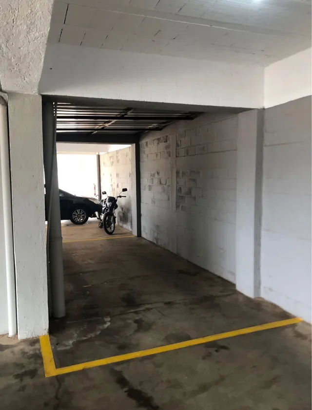 Foto de uma área de garagem com piso de concreto e estrutura branca.