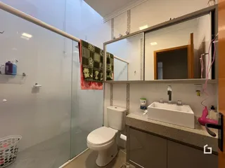Foto de um banheiro com box de vidro e louças brancas.
