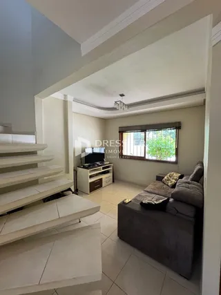 Imagem de uma sala de estar com escadaria e sofá.