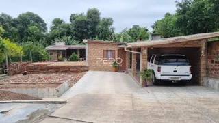 Vista externa de uma residência de tijolos com garagem e área pavimentada.