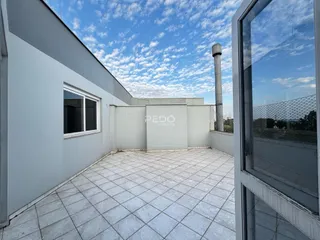 Vista externa de um pátio com piso de cerâmica e parede branca.