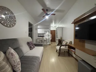 Sala de estar iluminada com sofá e televisão em um imóvel em Lajeado.